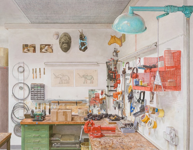 Aquarell: Eine Werkstattwand mit Werkbank, Schraubstock, Klebebandrollen und Werkzeugen, darüber hängen ein Gorillakopf, ein Pferdekopf und Zeichnungen von Elefanten, rechts eine türkisfarbene Lampe.